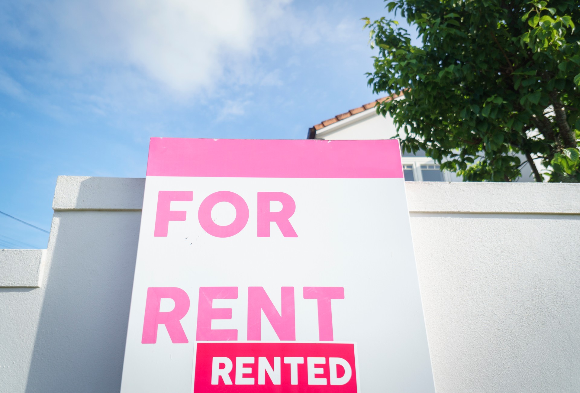 Hot rental market - House For Rent and Rented real estate sign in front of a house on the white fence wall. Auckland.